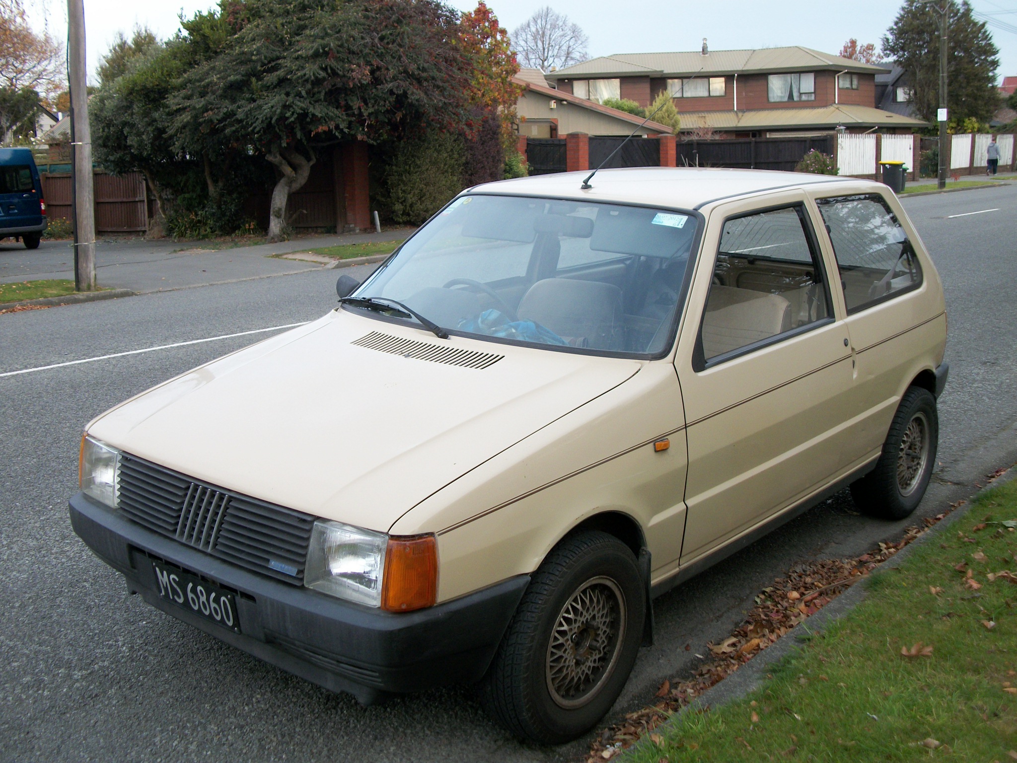 there is a dirty small car parked by the curb