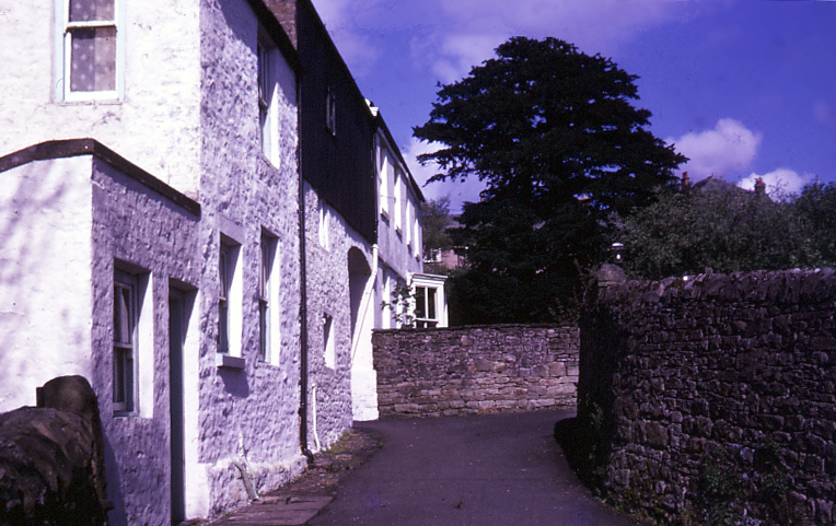 a stone wall and a walkway leading to some buildings
