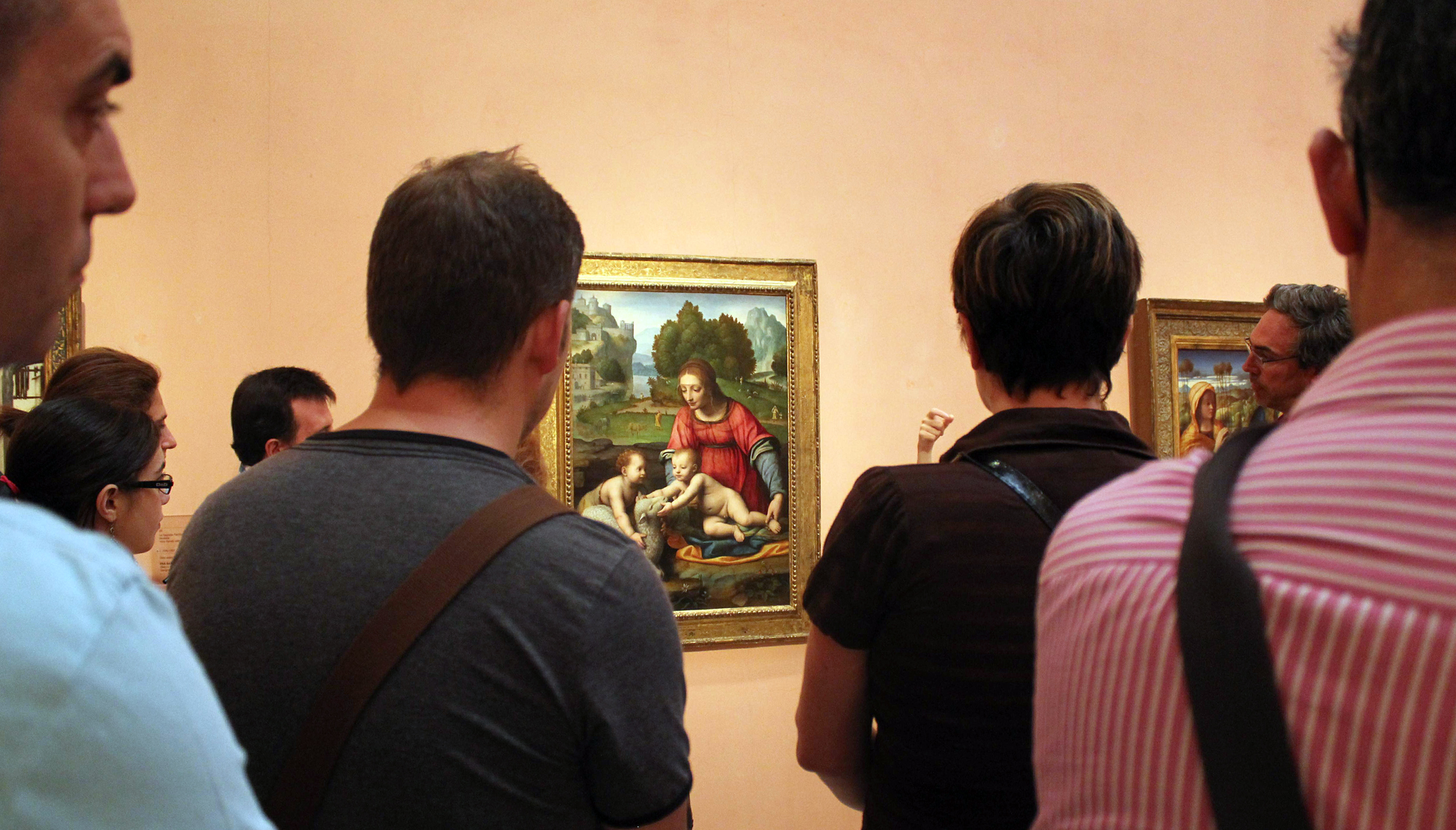 people looking at the artwork of a woman sitting on a bench