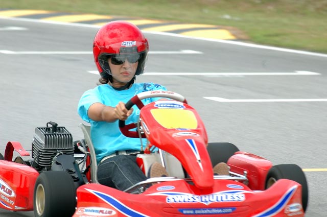 a small boy in blue shirt and helmet on small red car
