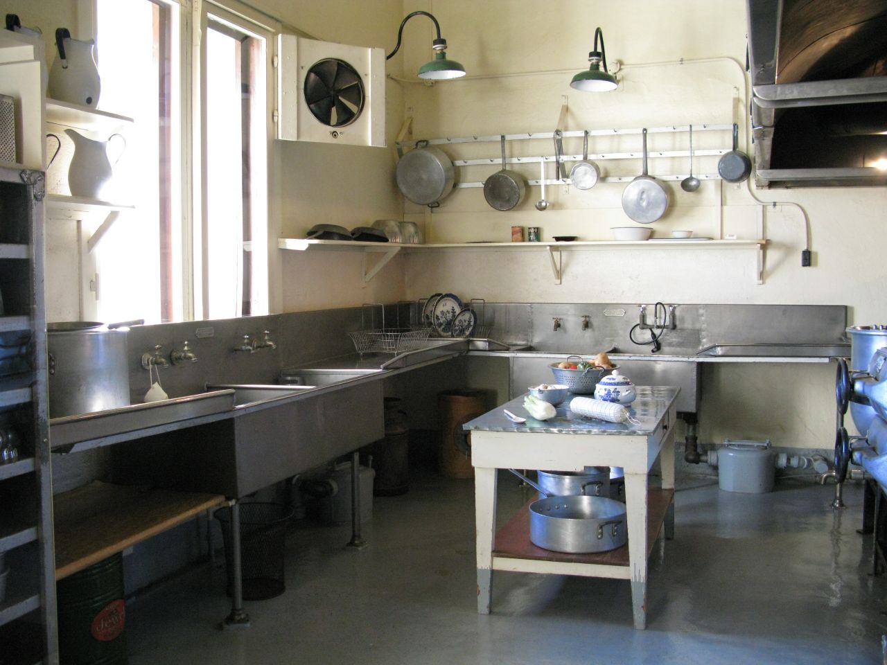 a kitchen with metal appliances and pots hanging from the ceiling