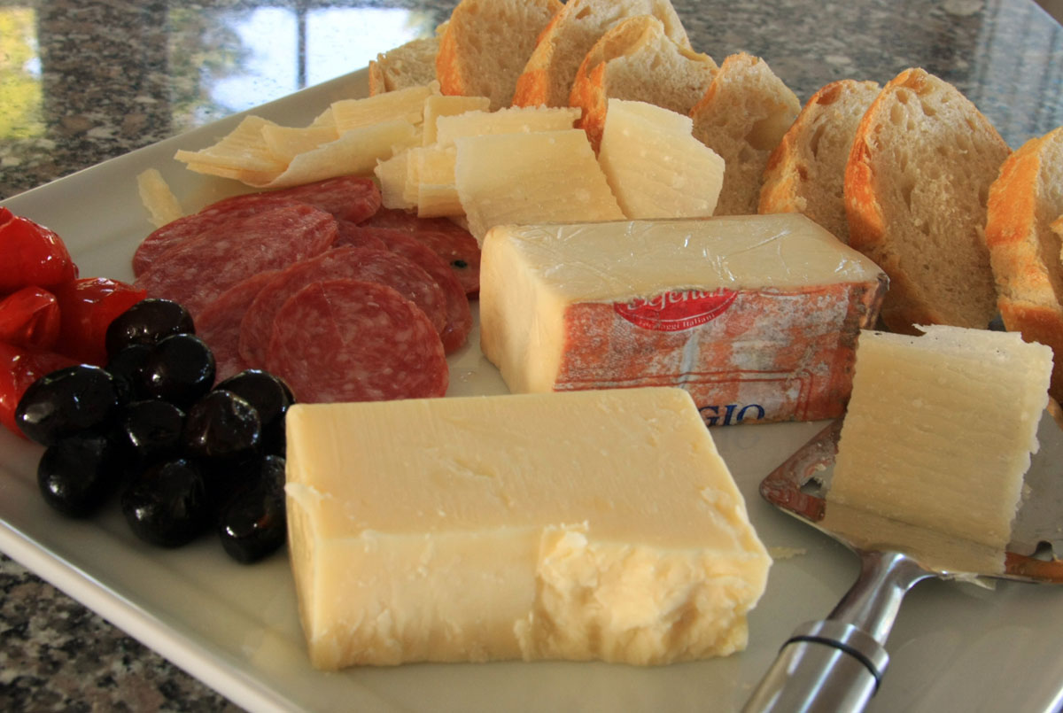 cheese and salamis arranged on a white plate