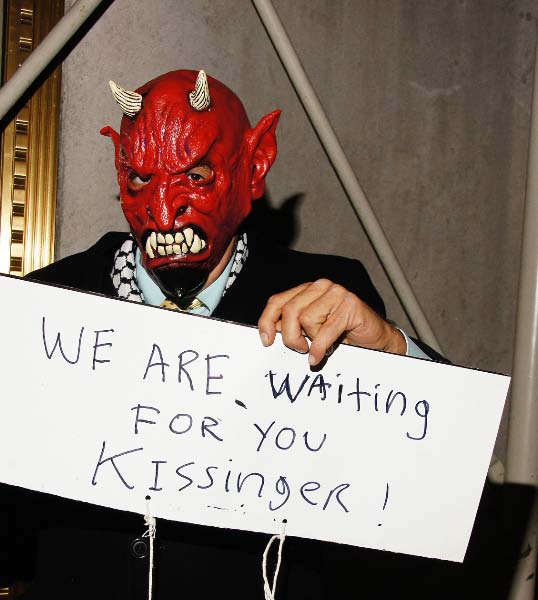 a man with red makeup holding a sign that says, we are waiting for you kissine