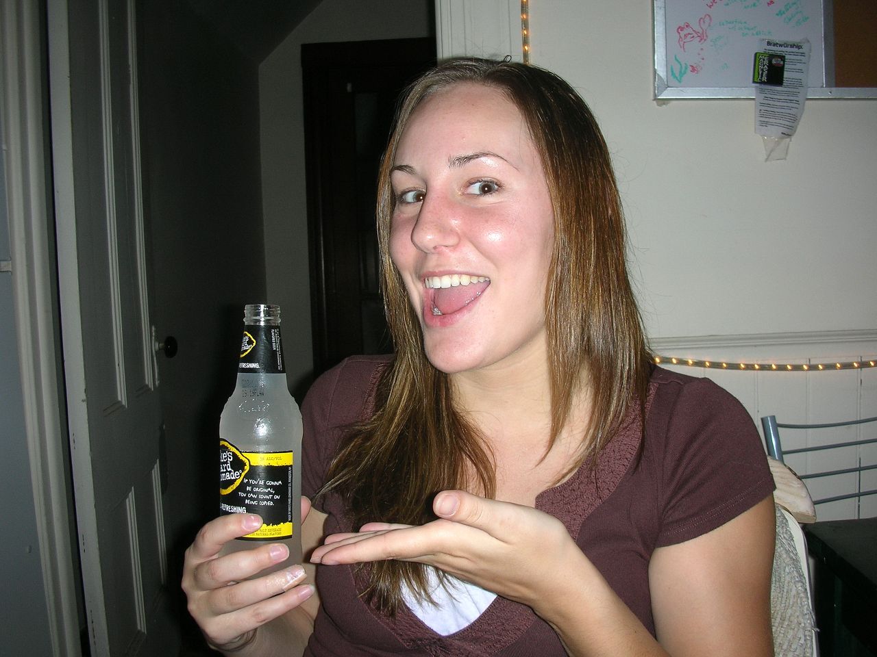 woman smiling while holding a bottle of beer