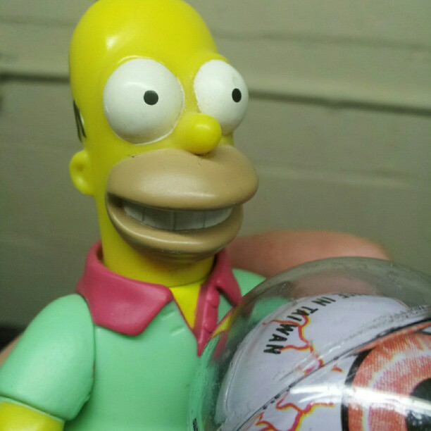 a action figure from the simpsons is posed with a ball