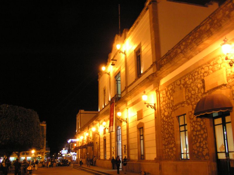 a row of buildings with people standing outside at night