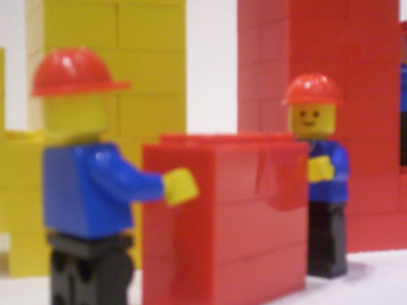 two lego figures are positioned around a yellow one
