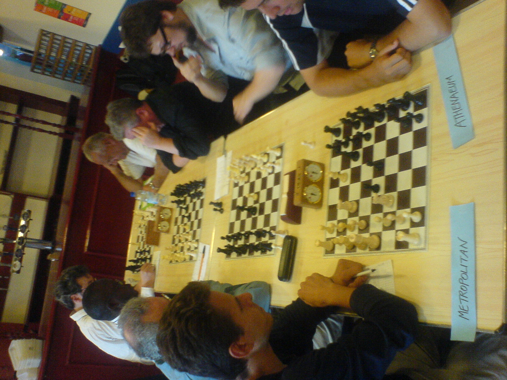 a group of people sitting at a table next to a table with chess pieces