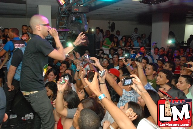 a man is standing in front of a crowd talking on a cell phone