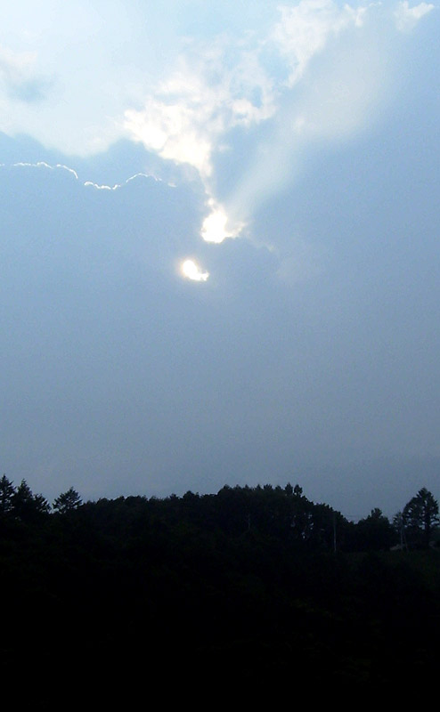 the sun peeking through a cloud covered sky