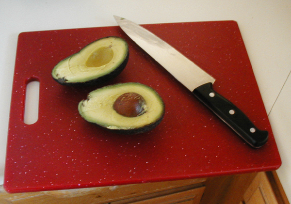 an avocado and knife sit on a  board