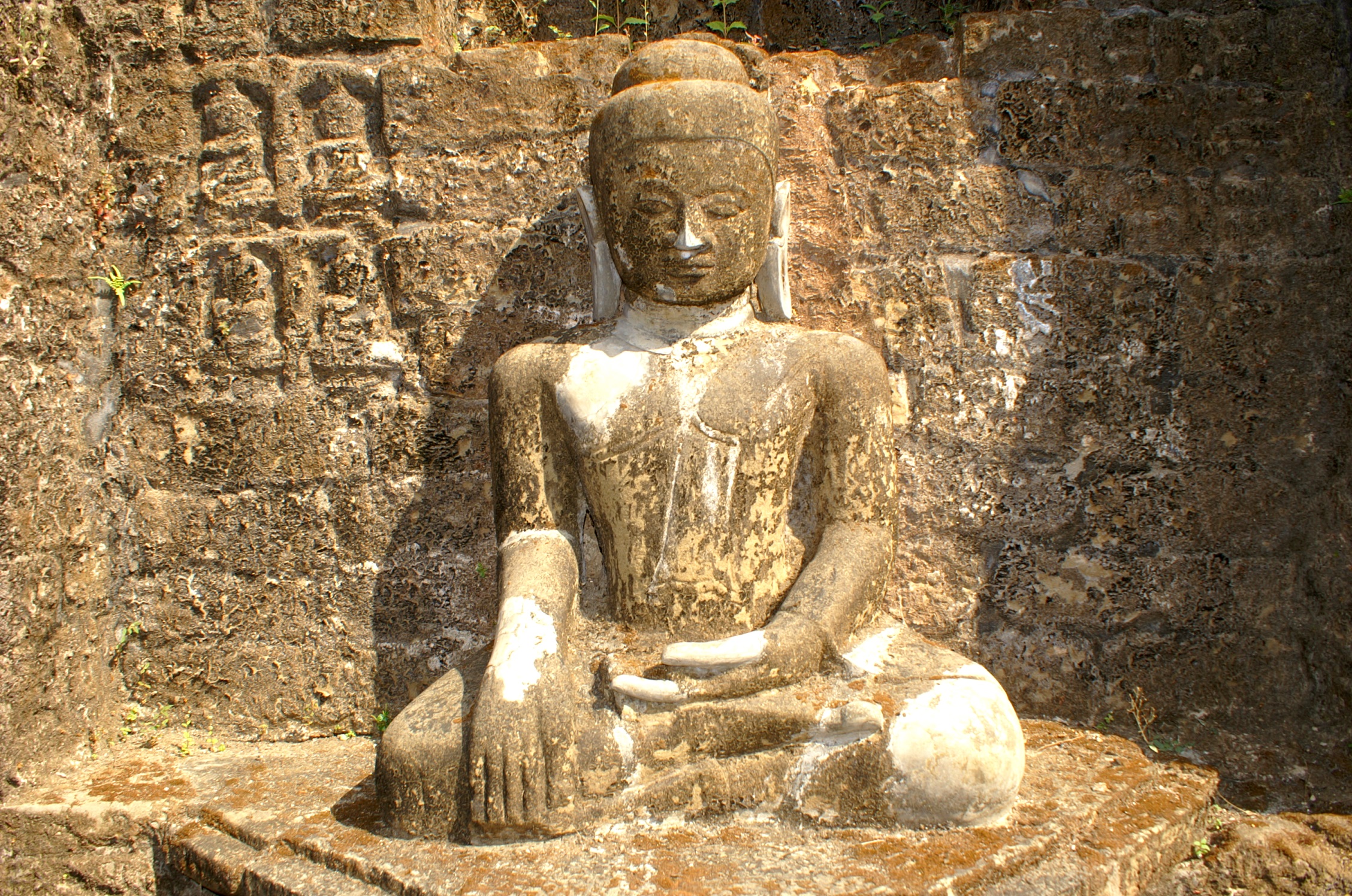 a very big stone statue near a wall