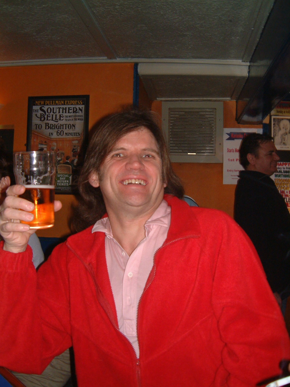 man drinking beer in a pub while posing for a po