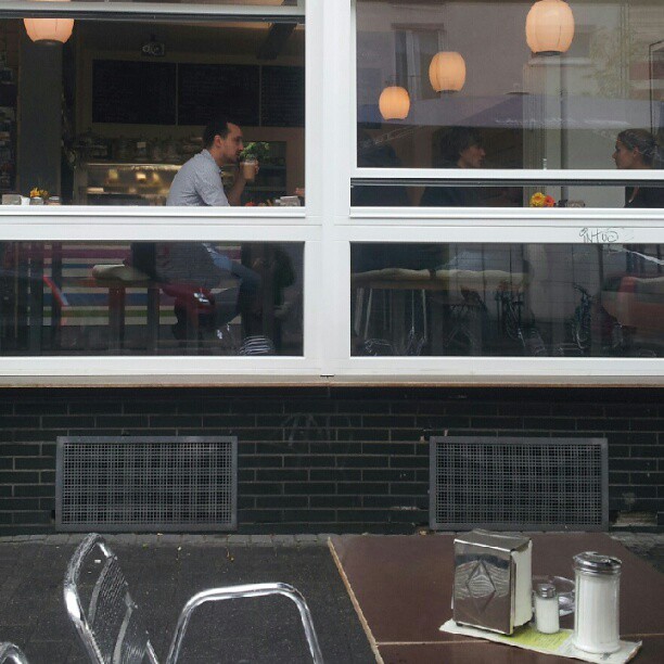a man sitting down at a restaurant table next to a building