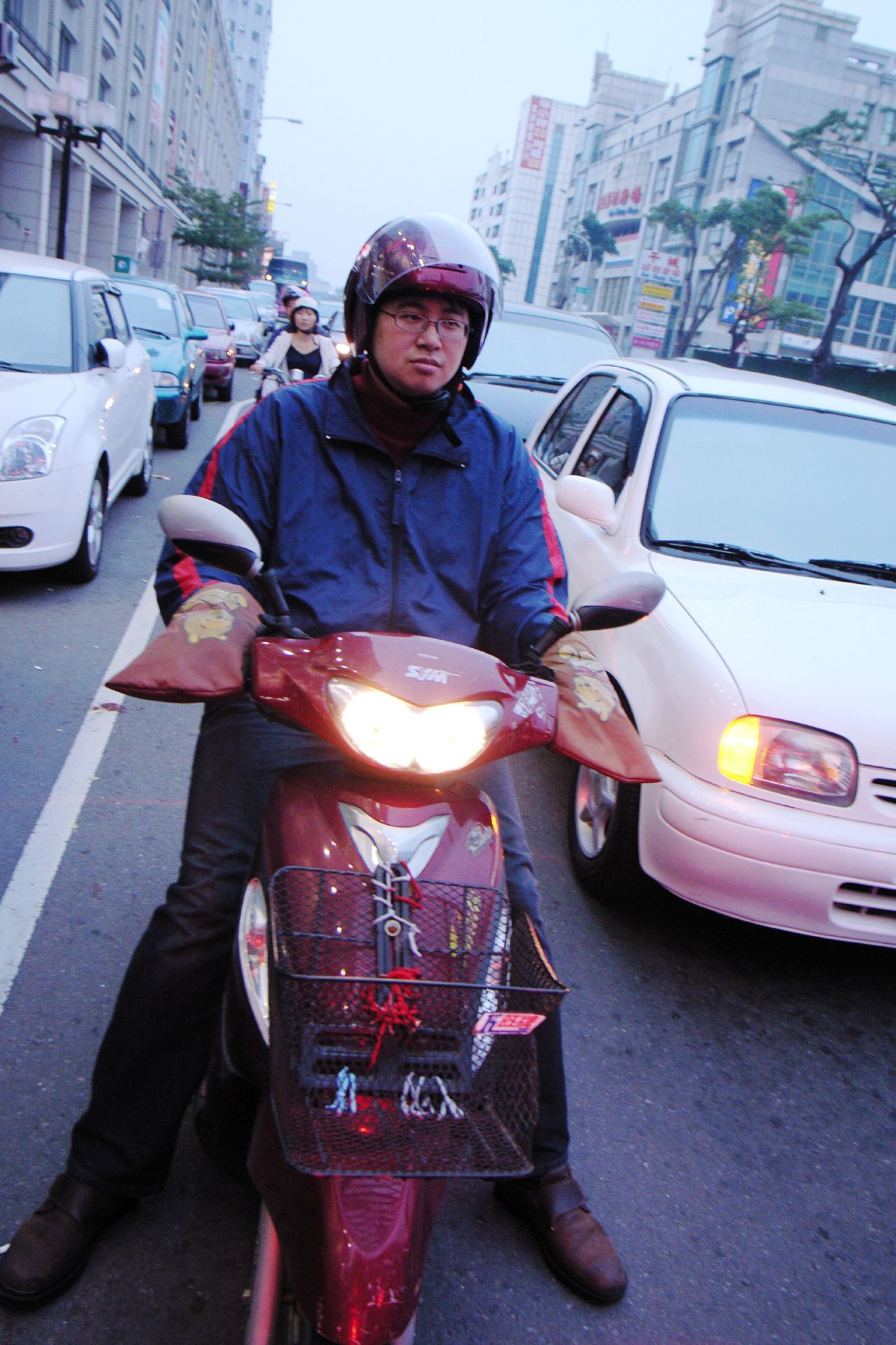 a man riding a red motorcycle down a busy street