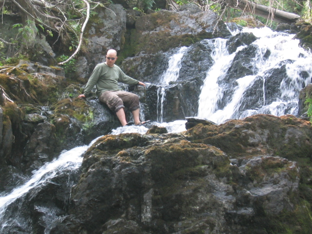 a man sits on the rocks next to a waterfall