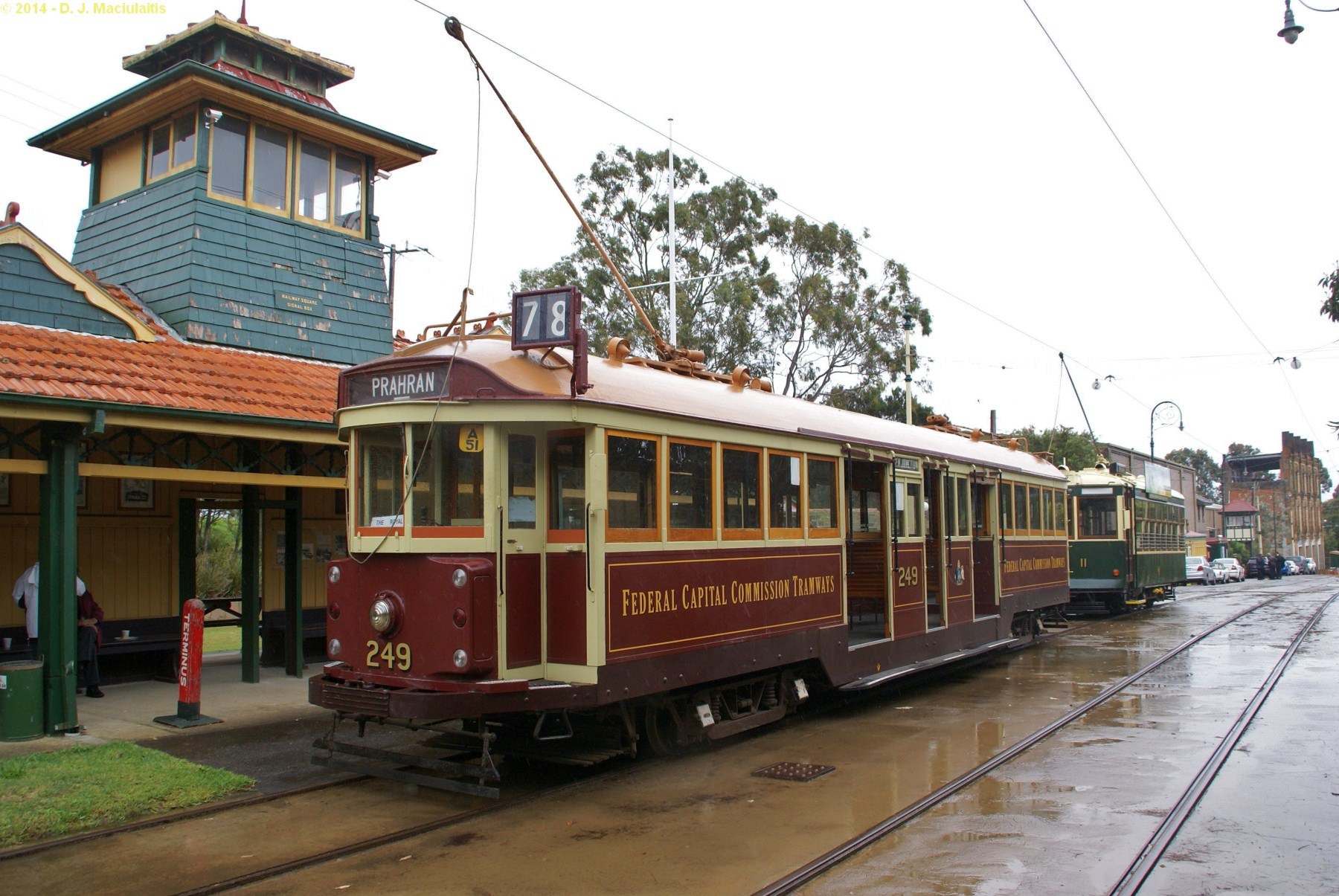 a red and tan trolley pulling into a station