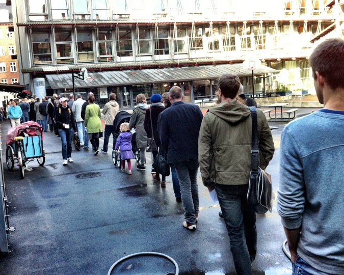 many people walking down a wet street with umbrellas on