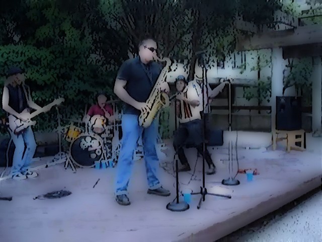 group of people playing instruments on stage in front of a house