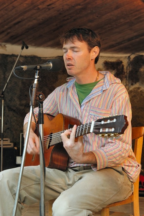 a man is playing a guitar on a stool