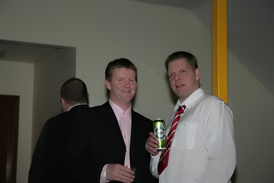 two men smiling while one holds a green beer