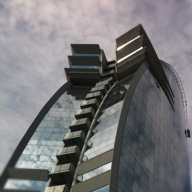 a large tall building with glass windows against a cloudy sky