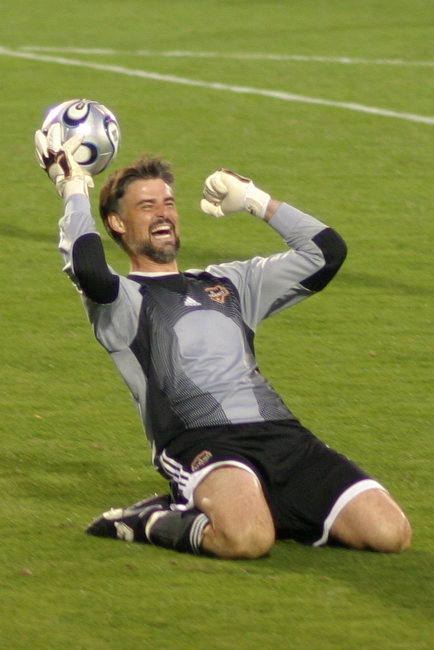 a soccer player with his arm in the air and holding a ball