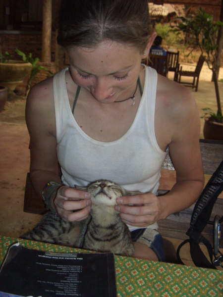 a woman holding and petting a cat on top of a table