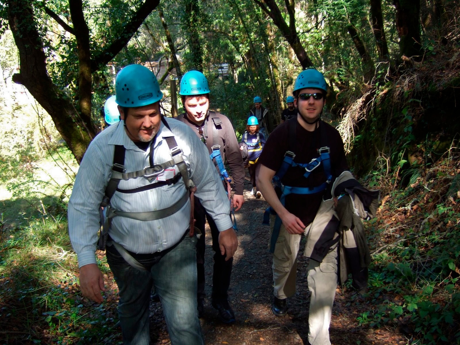 a group of men with helmets and safety equipment hiking in the woods