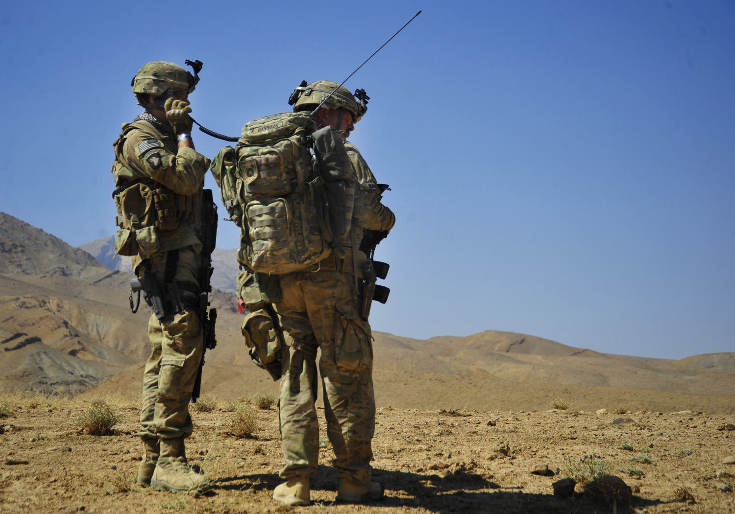 two soldiers standing on the desert, both looking at soing