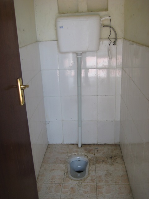 a small bathroom with an open door and white tiled walls