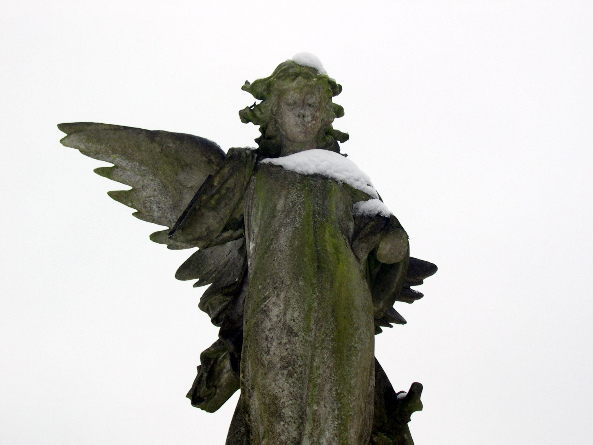 a statue with large wings is covered with snow