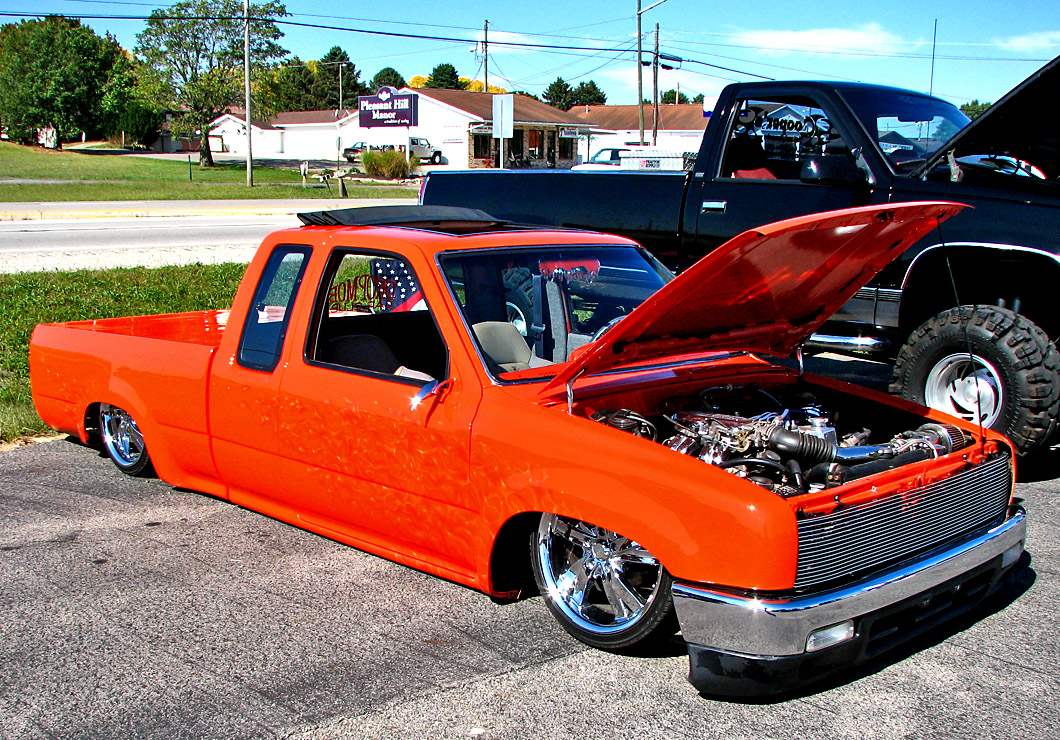 a orange truck parked in front of another black vehicle