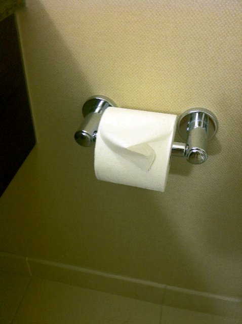 an empty bathroom stall with folded towels hanging on the handle