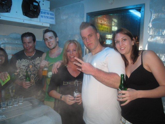 a group of people are standing in a room holding beer bottles and posing for a po