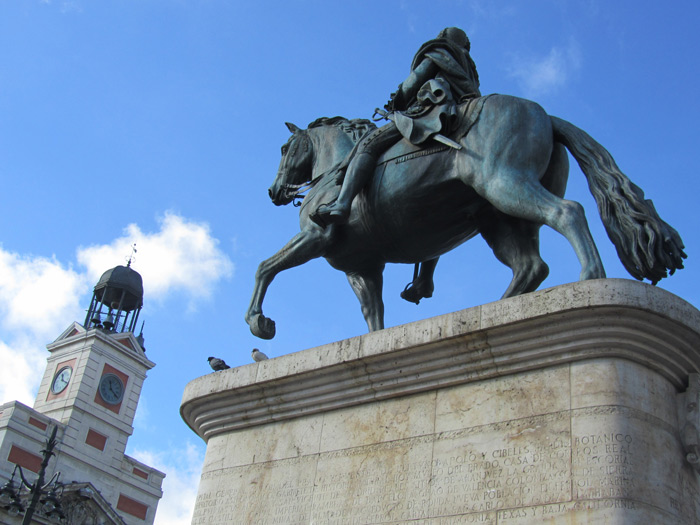 a statue of a man riding a horse, with a bird perched on top
