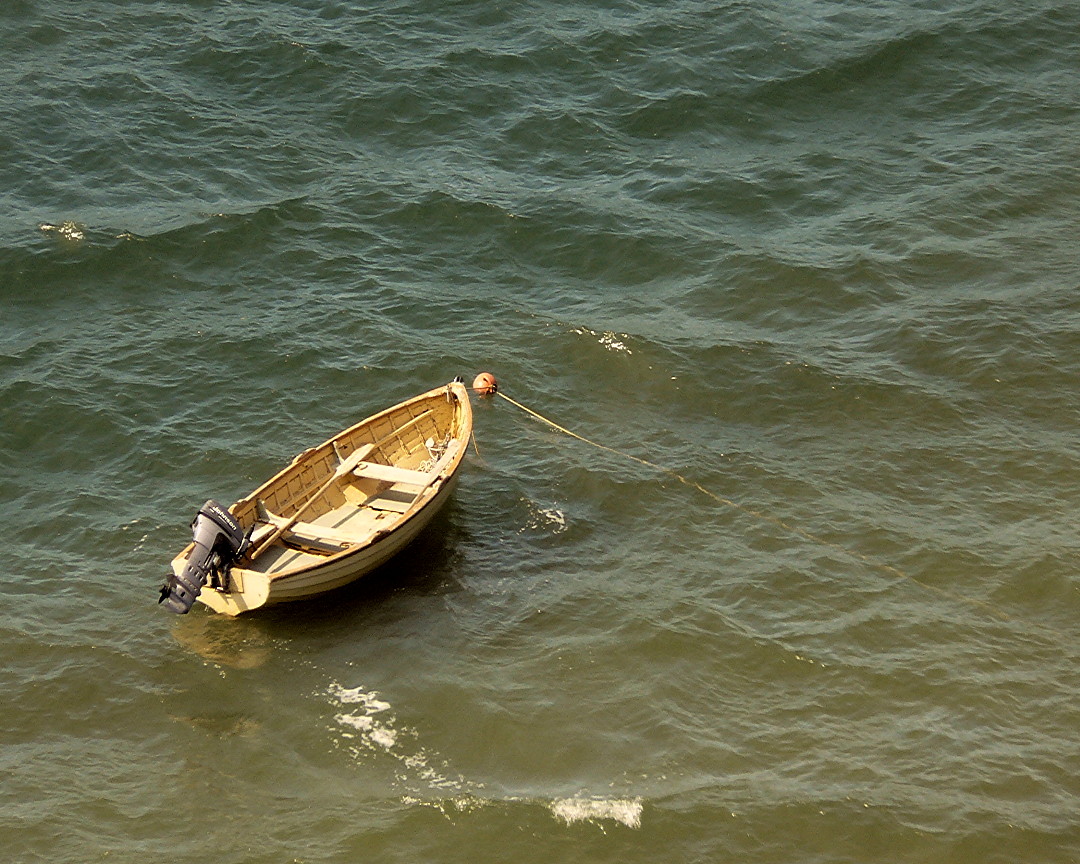 small boat with oar in the sea with people around