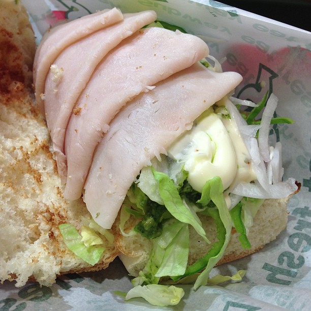 a sandwich with chicken and lettuce wrapped in paper