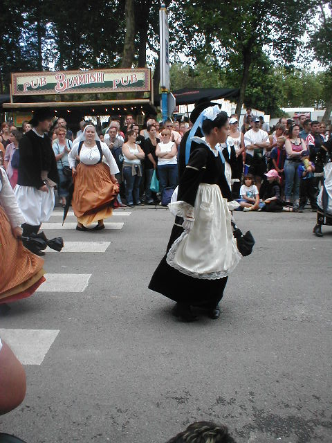 a group of people standing around in street with dancers