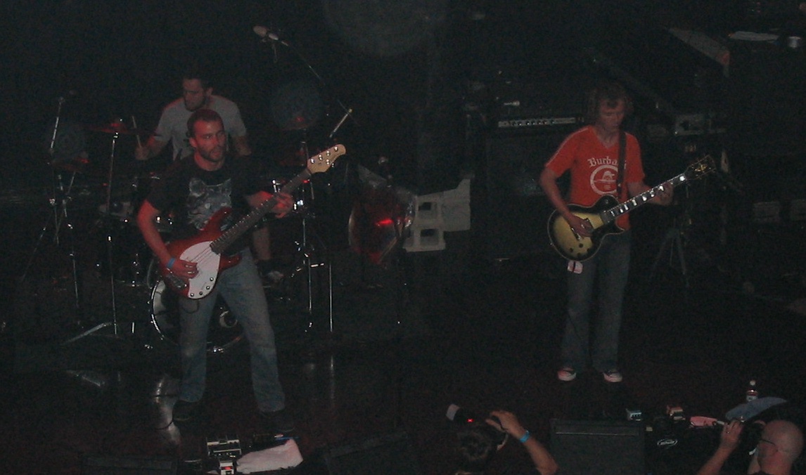 several people are playing guitars while on stage