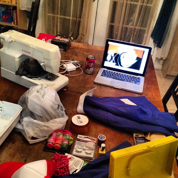 a cluttered kitchen with a laptop and several types of items on the table