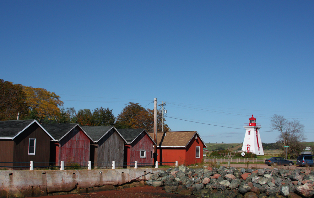 several red cottages with a light house in the background