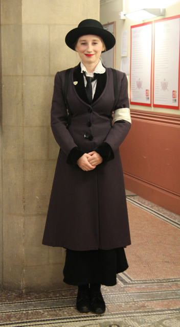 a woman dressed in black and standing next to a wall