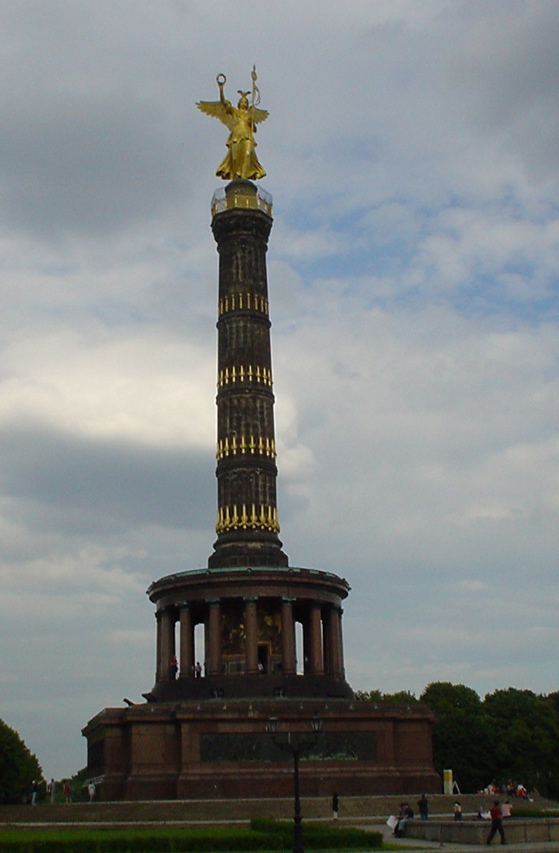 there is a statue on a tower with two golden statues in the background