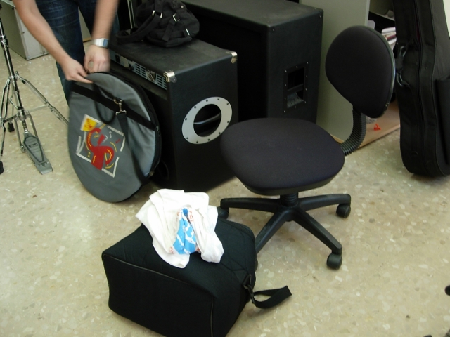 some black speakers on a chair next to another speaker and a pair of suitcases