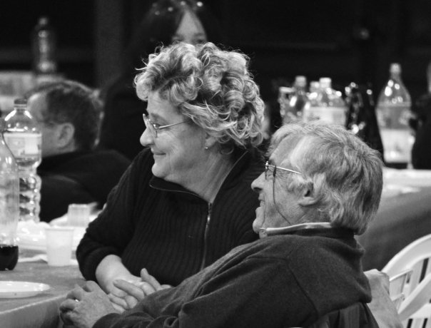 two people sit at a table together, one with her arms around the other