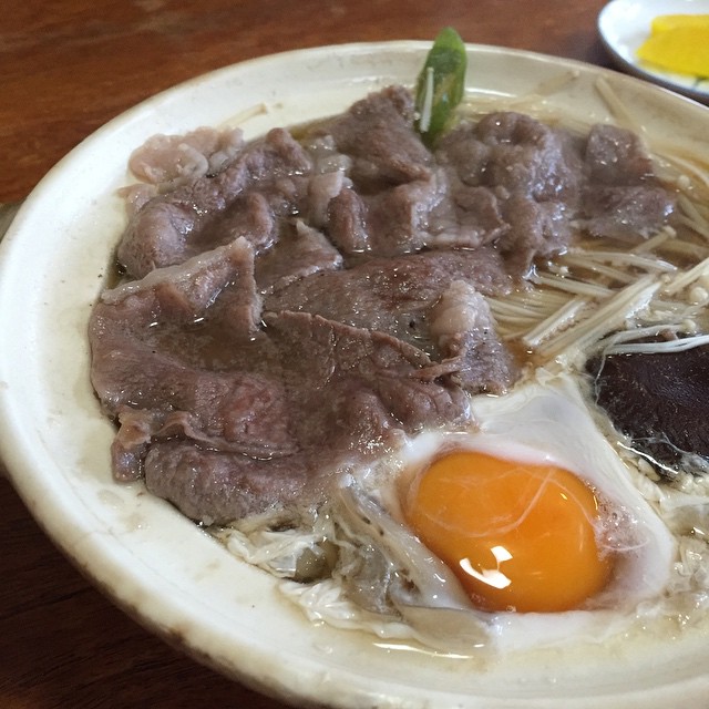 an open dish with eggs, meat and noodles