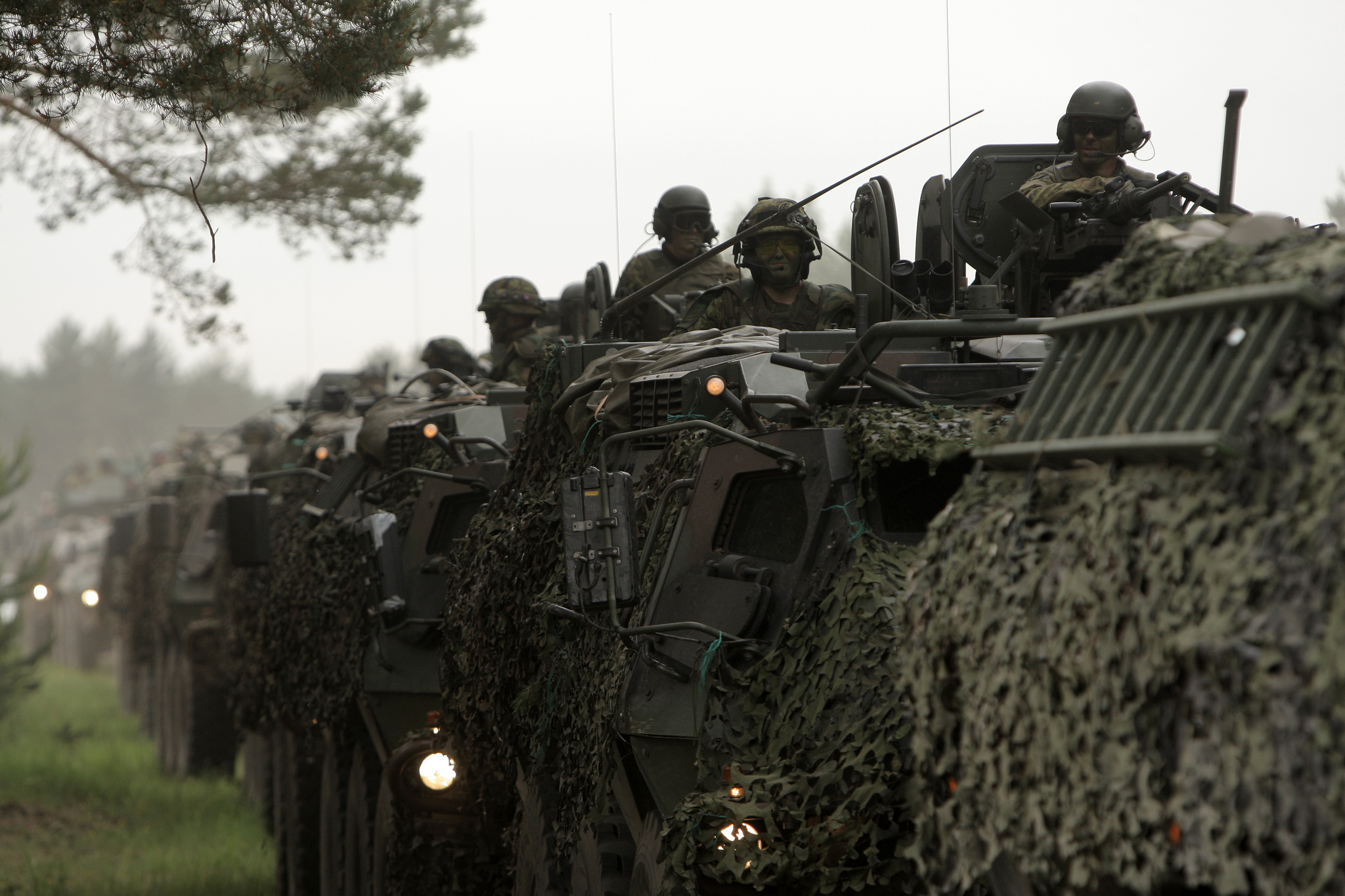 military men wearing camouflage gear sit in formation on top of vehicles