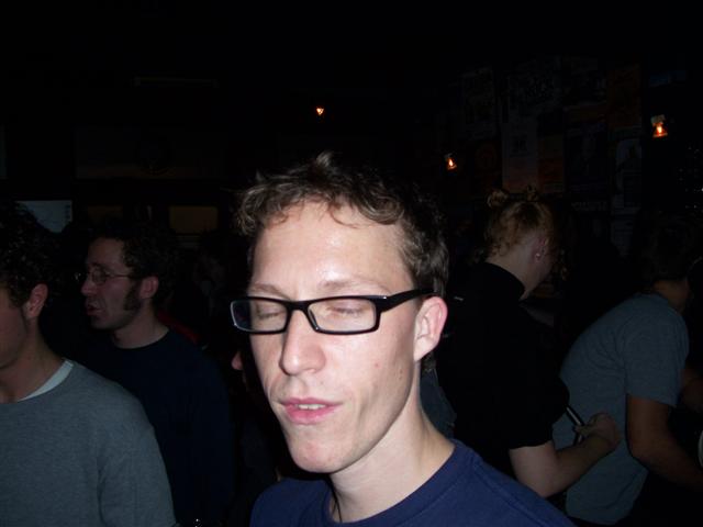the man has glasses on with a dark background