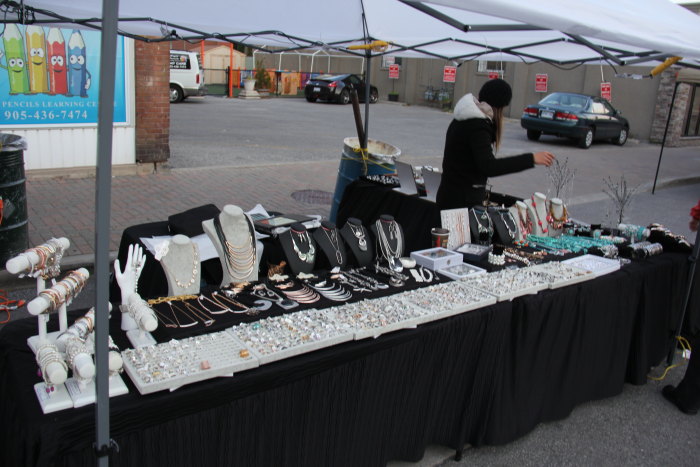 a woman is selling various jewelry on the table